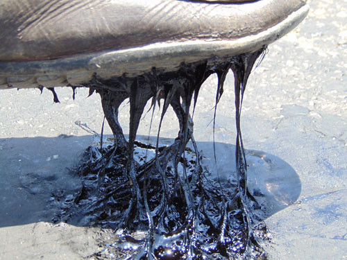 Nhựa đường chảy ra bám chặt vào đế giày. Ảnh: Đức Hùng.