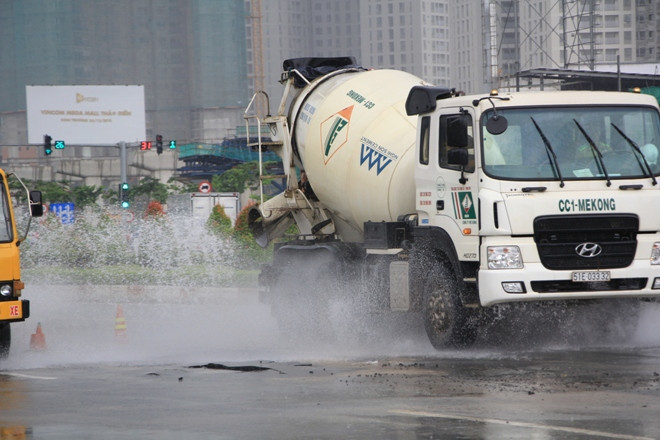 Xe cộ lưu thông qua khu vực nước máy tràn ra mặt đường đã làm nước bắn lên tung tóe