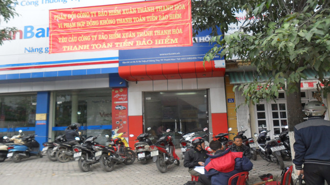 Đại diện Công ty CP Hoàng Thịnh treo băng rôn và ngồi trước cửa yêu cầu công ty Bảo hiểm Xuân Thành Thanh Hóa thanh toán tiền bảo hiểm. Ảnh: Phạm Nhài.