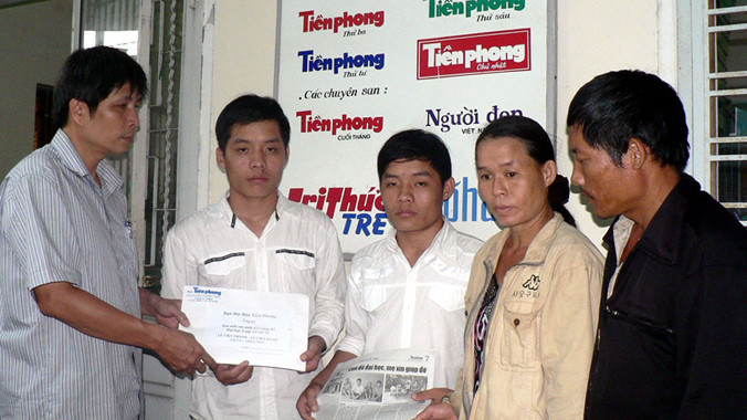 Đại diện báo Tiền Phong trao số tiền bạn đọc giúp đỡ cho hai anh em Danh - Thành với sự có mặt của ba mẹ hai em (ảnh chụp tháng 9/2009). ảnh: N.H