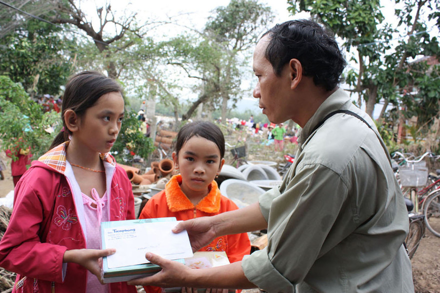 Nhà báo Nguyễn Đình Quân trao sách vở và 2 triệu đồng cho chị em Thu Hồng – Như Ngọc (Tuy An – Phú Yên) có cha và mẹ chết trong trận lũ tháng 11/2009 để giúp sức đến trường. Ảnh Nguyễn Thành, chụp ngày 9/11/2009