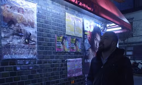 Một người đàn ông đi qua bức tường dán đầy quảng cáo mại dâm nam ở Nicho, Tokyo. Ảnh: SCMP.