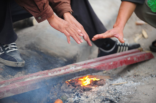 Tại trung tâm Hà Nội, nhiệt độ là 15 độ C. Những người lái xe ôm, buôn bán ngoài đường đốt lửa sưởi ấm. Ảnh: Giang Huy. 