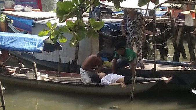 Người phụ nữ được đưa lên ghe và sơ cứu tại chỗ, may mắn thoát chết.