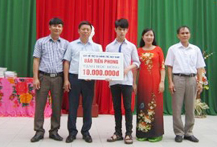 Ông Trần Thanh Lâm, Phó Tổng Biên tập Báo Tiền Phong, Phó giám đốc Quỹ hỗ trợ tài năng trẻ Việt Nam cùng đại diện lãnh đạo địa phương, nhà trường trao tặng học bổng cho em Lê Đức Hậu. Ảnh: Hoàng Lam