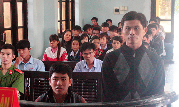 Bị cáo Phan Phụng Phước (đứng) và Lê Văn Tư tại phiên tòa. Bị cáo Tư đã bị cụt một chân nên suốt phiên xử được phép ngồi.