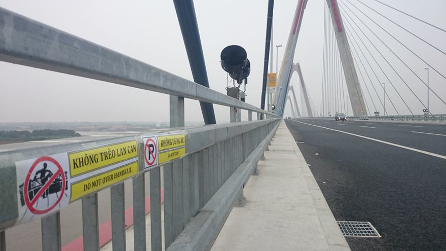 Các công nhân dán các tấm biển trên cầu Nhật Tân.