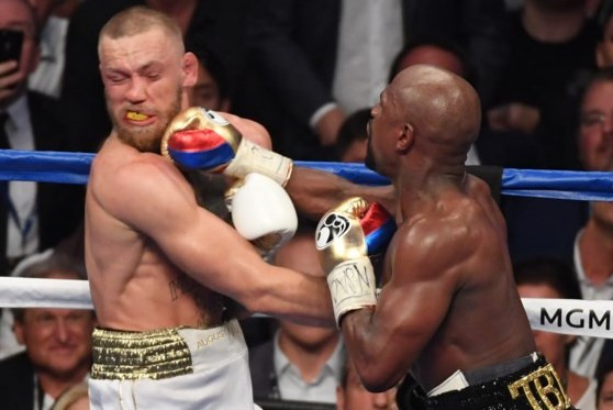 Conor McGregor (trái) dính một đòn nặng từ Mayweather.