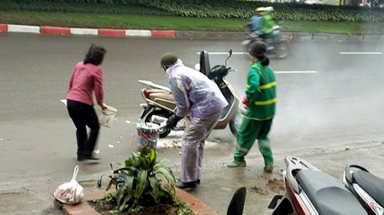 Hai phụ nữ giúp chủ xe (áo mưa tím) dập lửa.