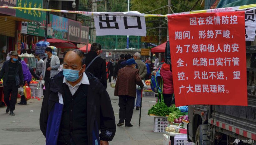 Một người đeo khẩu trang đi qua thông báo về thực hiện các biện pháp kiểm soát COVID-19 ở Lan Châu ngày 25/10. (Ảnh: AP)