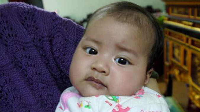 Mặc dù còn ẵm ngửa trên tay nhưng con chị Hương đã biết nói. Ảnh infonet.