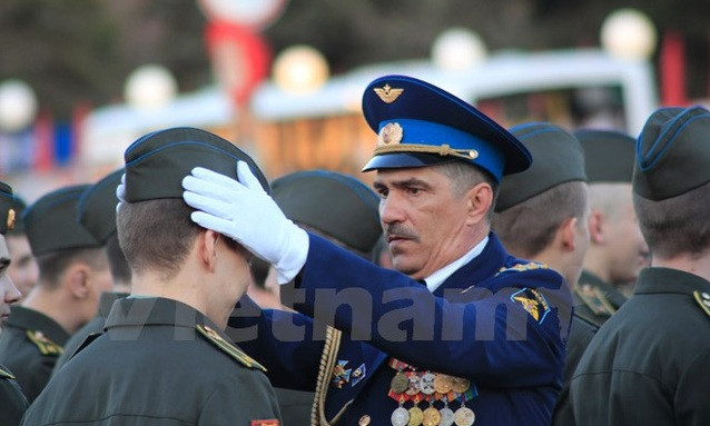 Sỹ quan chỉ huy căn chỉnh trang phục cho chiến sĩ trẻ trong đội diễu binh. (Ảnh: Trần Hiếu/Vietnam+)