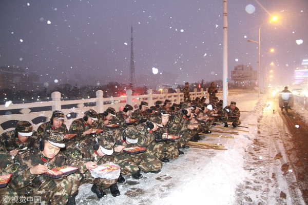 Những người tính ăn tối ven đường để có thể dọn sạch tuyết càng sớm càng tốt ở Tú Thiên, Giang Tô, vào ngày 4/1. Ảnh: VCG