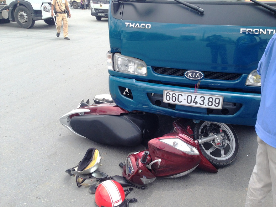 Chiếc xe máy kẹt dưới gầm xe tải.