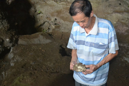 Già làng Lục Liên Thưởng, 70 tuổi cầm chiếc bát cổ đã bị vỡ trong hang.