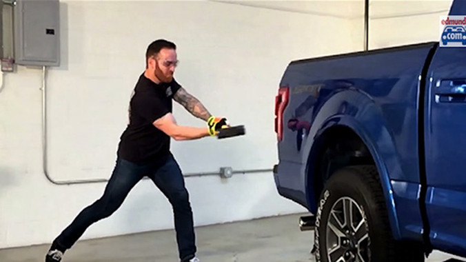 Một phóng viên nước ngoài đang dùng búa tạ thử sức chịu đựng của Ford F-150.