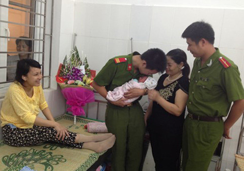 Con trai chị Phương trong vòng tay của hai cảnh sát đỡ đẻ giữa cơn giông
