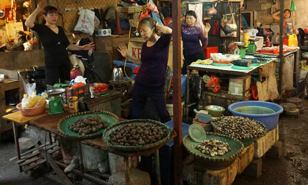 Chị Chử Oanh (58 tuổi, đứng giữa) là một trong những người phổ biến môn thể thao này về đây đầu tiên. Ngay tại sạp hàng bán cua ốc của mình, cứ đúng 11h là chị bật nhạc báo hiệu cho chị em xung quanh bắt đầu vào buổi tập