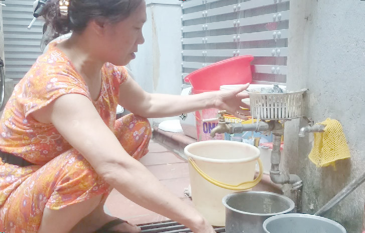 Bác Chu Thị Oanh vặn vòi nước nhưng không hề có một giọt nào. Ảnh: Thanh Hà.