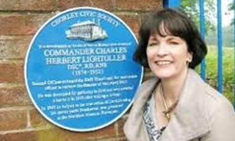 Tiểu thuyết gia L. Patten bên tấm biển tưởng nhớ ông nội, được gắn trước cổng ngôi trường ông từng theo học tại thị trấn Chorley quê hương.