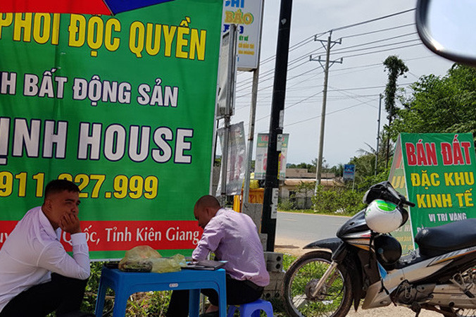 Nhân viên tiếp thị đất dựng pa nô, che dù ngoài vỉa hè để rao bán đất. Ảnh: Việt Tường.