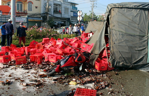 Xe máy của đôi nam nữ bị thùng bia đè lên.