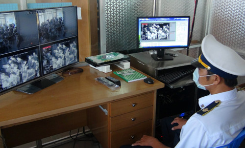 Nhân viên Y tế theo dõi, kiểm tra thân nhiệt hành khách trên màn hình. Ảnh: Phạm Thanh Tân-TTXVN