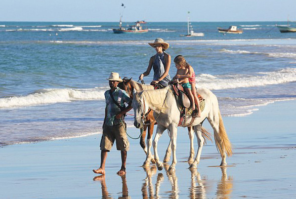 Bà mẹ hai con cùng các con cưỡi ngựa dạo trên biển.