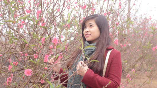 Nữ sinh rạng rỡ bên hoa đào trong tiết trời đông