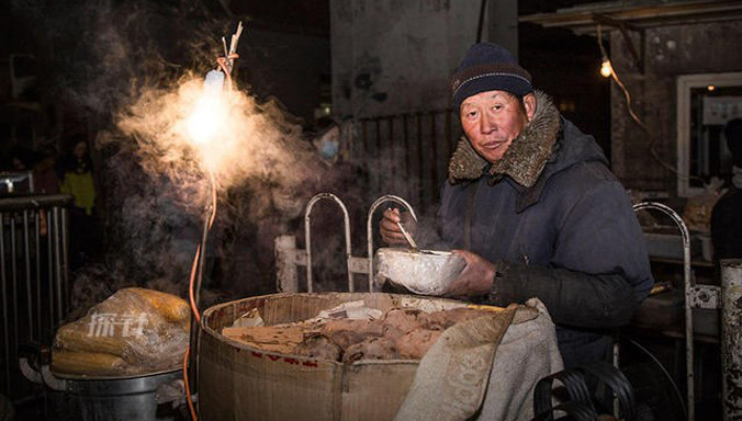 Người đàn ông ngồi bán ngô trên đường phố trong giá rét kỷ lục ở Bắc Kinh.