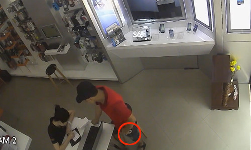 Lợi dụng lúc nhân viên không chú ý, thanh niên rút điện thoại dấu xuống bàn rồi hắn đứng dậy đút chiếc điện thoại vào túi quần.