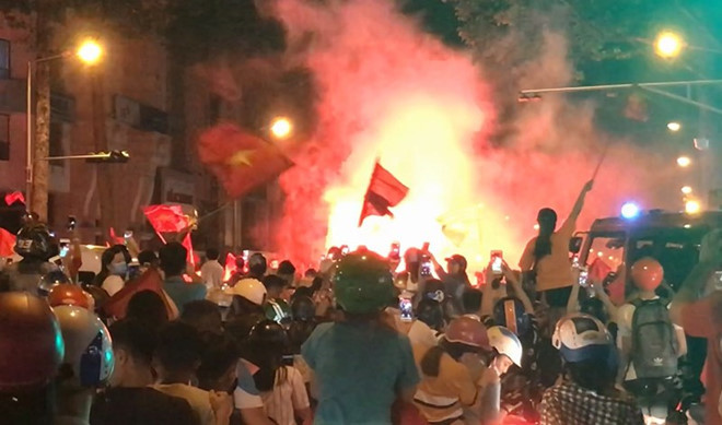 Cổ động viên đốt pháo sáng rực trên đường Trần Hưng Đạo, quận 1. (Ảnh: L. THOA)