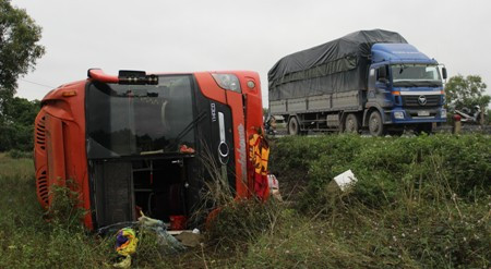 Chiếc xe khách lao xuống hành lang bên đường rồi lật nghiêng.