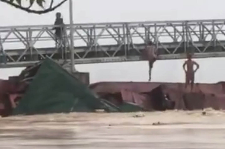 Ba người trên xà lan trèo lên cầu thoát thân. Ảnh chụp từ clip đăng trên facebook Nguyễn Đức Quang.