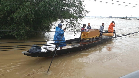 Người dân chèo đò mua quan tài về lo hậu sự cho nạn nhân Quý bị lũ cuốn trôi. Ảnh: K.T