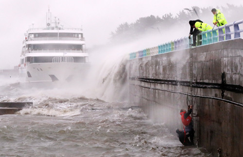 Các thuyền viên được giải cứu sau khi bị sóng cuốn khỏi cầu cảng ở miền nam Hàn Quốc. Ảnh: Yonhap.