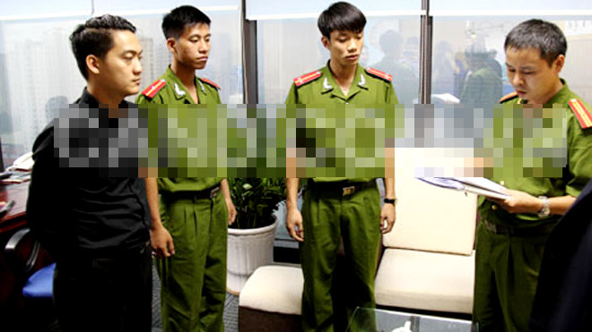 Đối tượng Phạm Kiện Trung (áo đen) nghe đọc lệnh bắt khẩn cấp. Ảnh: CAND