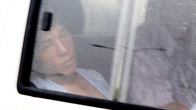 Tuấn bị cảnh sát áp giải. Ảnh: Quốc Thắng