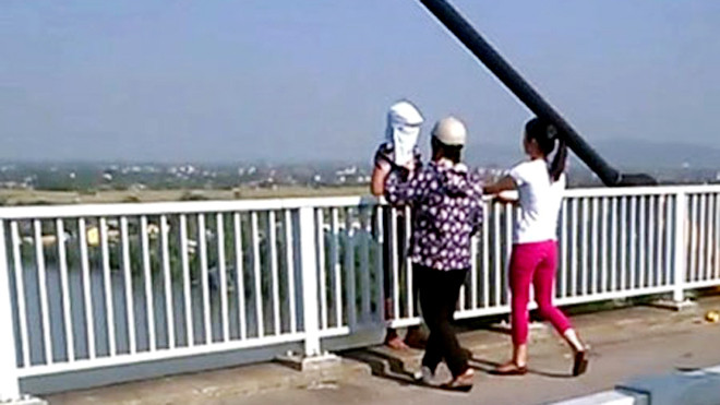 2 nữ cảnh sát mặc thường phục tiếp cận người phụ nữ định nhảy cầu (ảnh cắt ra từ clip do người dân cung cấp) để thuyết phục, động viên