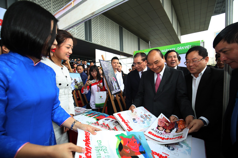 Tổng Biên tập báo Tiền Phong Lê Xuân Sơn giới thiệu các ấn phẩm của báo với Thủ tướng Nguyễn Xuân Phúc tại gian hàng.