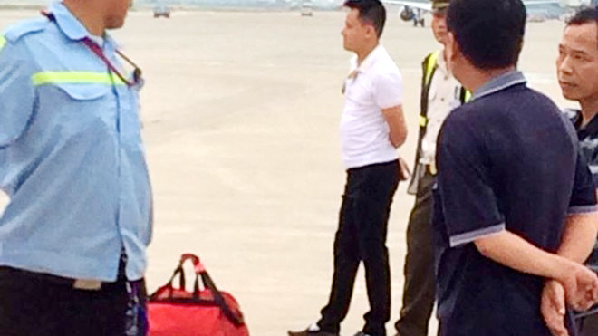 Nam hành khách (áo trắng) bị khống chế cùng hành lý xách tay nghi có bom. Ảnh: Zing