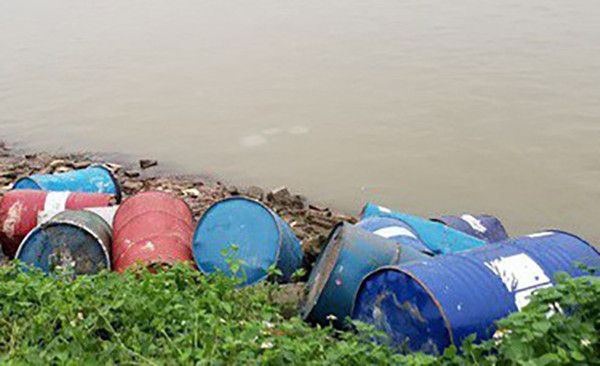 Hàng chục thùng phuy lạ rò rỉ chất đen xì mùi nồng nặc đổ xuống sông Hồng