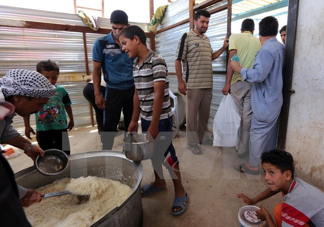 Trẻ em Iraq xếp hàng nhận lương thực cứu trợ tại khu vực Dora, ngoại ô thủ đô Baghdad ngày 31/5, sau khi phải rời bỏ nhà cửa ở khu vực chiến sự. (Nguồn: AFP/TTXVN)