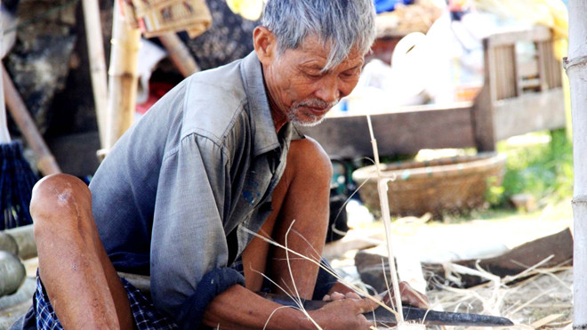 Lão Liêm miệt mài gắn bó với nghề đan thuyền thúng thủ công. ẢNH: NGUYỄN HUY