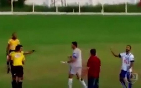 Trọng tài chính với khẩu súng trên tay đang chĩa vào một cầu thủ đã tấn công và đe dọa mình trên sân.