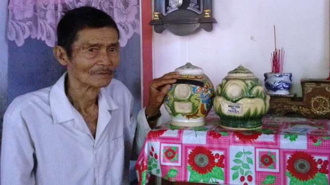 Ông Huỳnh Văn Châu bên hũ hài cốt của cha mẹ cất trên bàn thờ. Ảnh: Hòa Hội