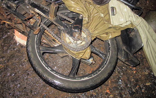 Áo mưa bị cuốn vào bánh sau xe, siết cổ nạn nhân tử vong. Ảnh: Khánh Hương.