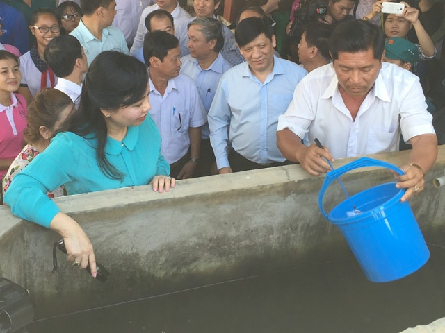 Bộ trưởng Nguyễn Thị Kim Tiến kiểm tra lăng quăng tại bể chứa nước nhà số D5/9B khu phố 4, thị trấn Tân Túc, huyện Bình Chánh, TPHCM. Ảnh: Quốc Ngọc