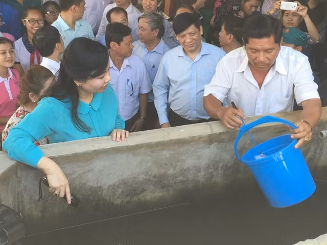 Bộ trưởng Nguyễn Thị Kim Tiến kiểm tra lăng quăng tại bể chứa nước nhà số D5/9B khu phố 4, thị trấn Tân Túc, huyện Bình Chánh, TPHCM. Ảnh: Quốc Ngọc