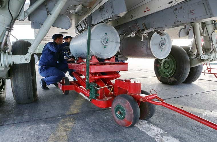 Các kĩ thuật viên không quân Nga đang lắp quả bom lên giá treo bụng máy bay cường kích Su-24 tham gia cuộc tập trận.